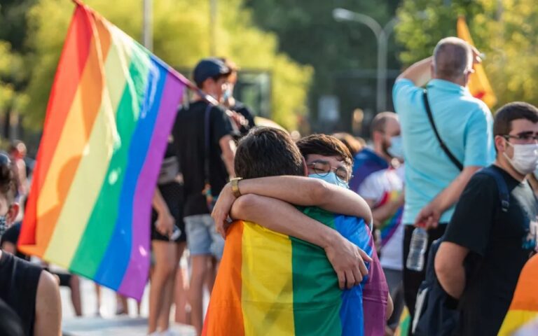 chiques abrazandose con la bandera LGBT