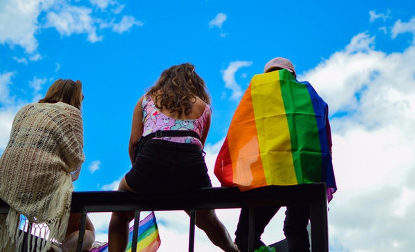 Personas con la bandera LGBT sentadas