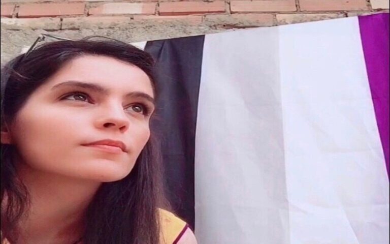 Olivia Ávila frente a la bandera de la asexualidad