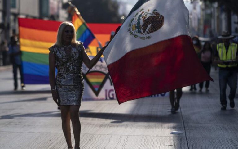 Persona con la bandera de México marchando por la prohibición de las terapias de conversión