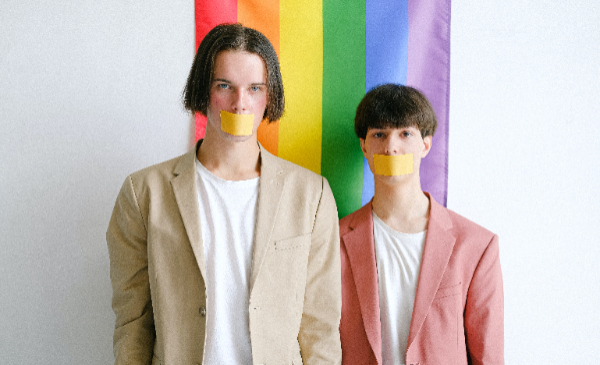 Dos personas con la bandera LGBT de fondo