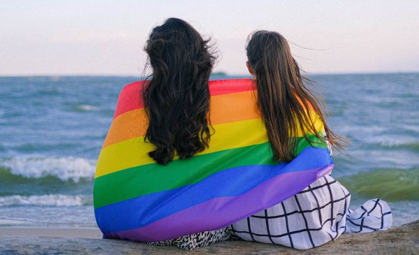 Dos personas con la bandera LGBT en la espalda