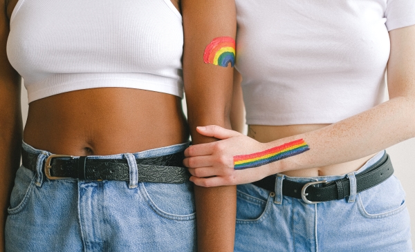 Dos mujeres con pintura de arcoiris en los brazos