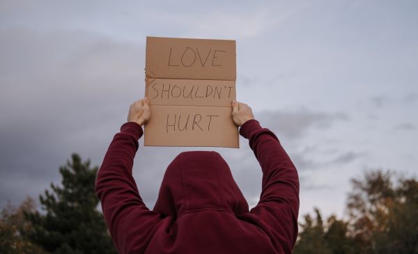 Persona con un cartel que dice "Love never hurts"