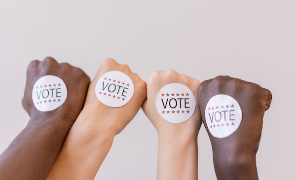 Mano de mujeres con stickers pidiendo el voto femenino